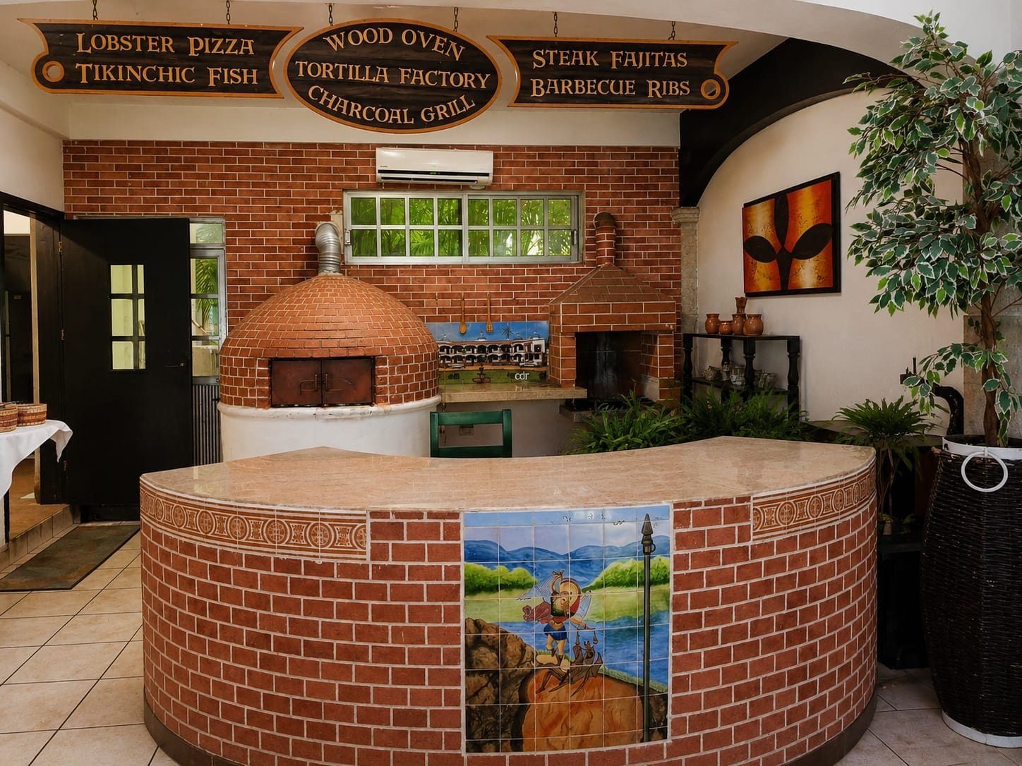Interior de restaurante com parede de tijolos, forno a pizza e um mural.