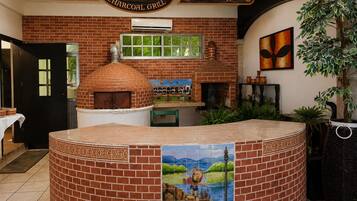 Interior de restaurante com parede de tijolos, forno a pizza e um mural.