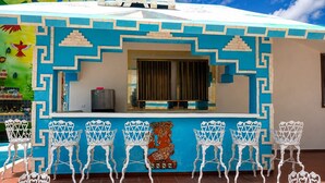 Un bar con una decoración azul y blanca, sillas blancas y piso de baldosas.