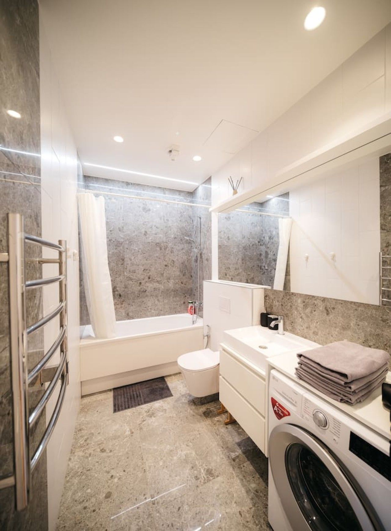 A modern bathroom with a bathtub, toilet, and washing machine.
