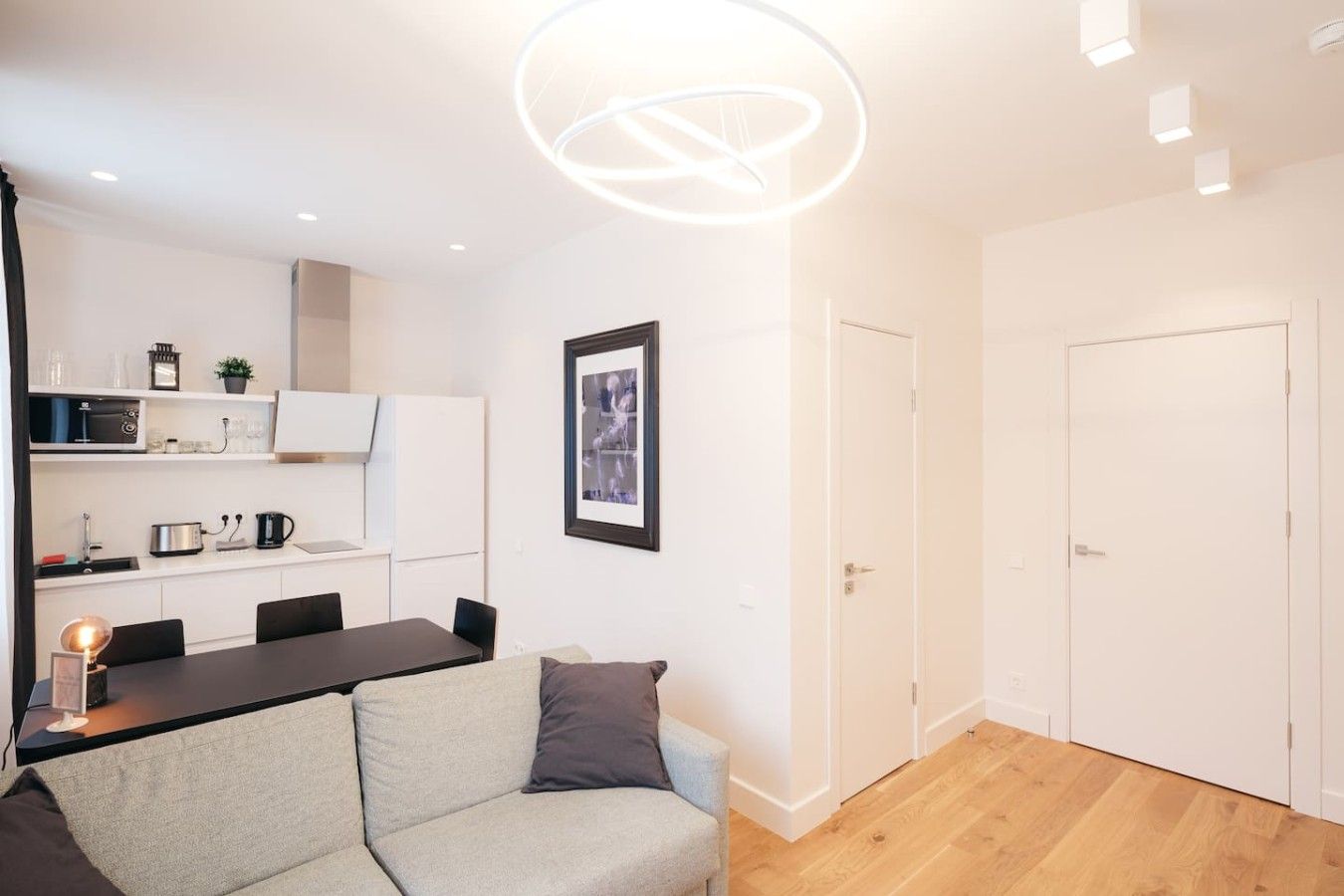 Un appartement moderne comprenant un coin repas, une kitchenette et un espace de vie avec un canapé et un tableau encadré au mur.