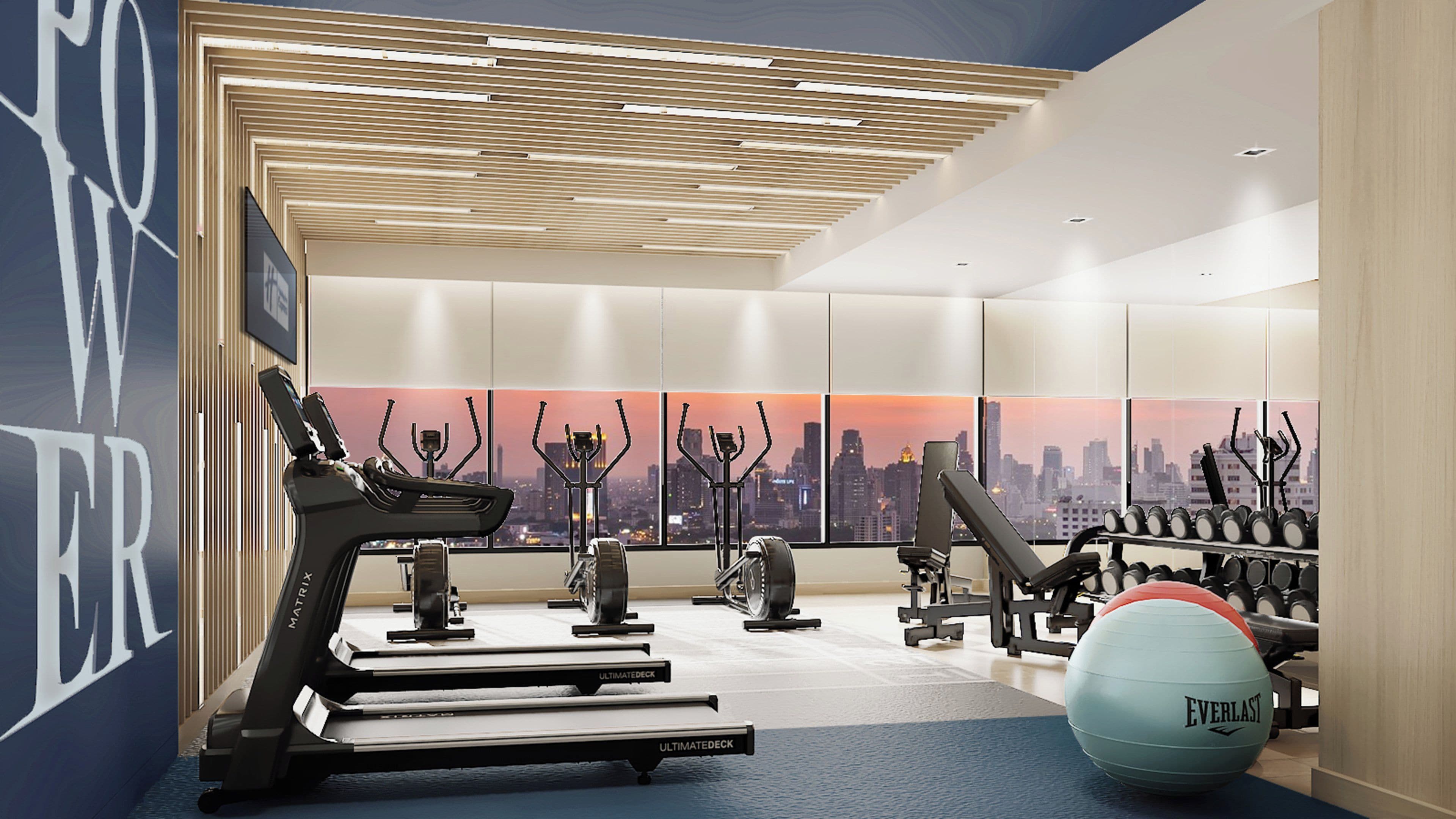 A modern gym with treadmills, elliptical machines, and exercise balls.