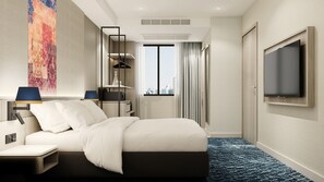 Quarto de hotel com cama, escrivaninha, televisão e uma grande janela com vista para a cidade.