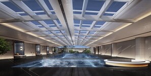 Un vaste espace intérieur doté d’une grande piscine moderne, de lucarnes et d’un espace salon circulaire.