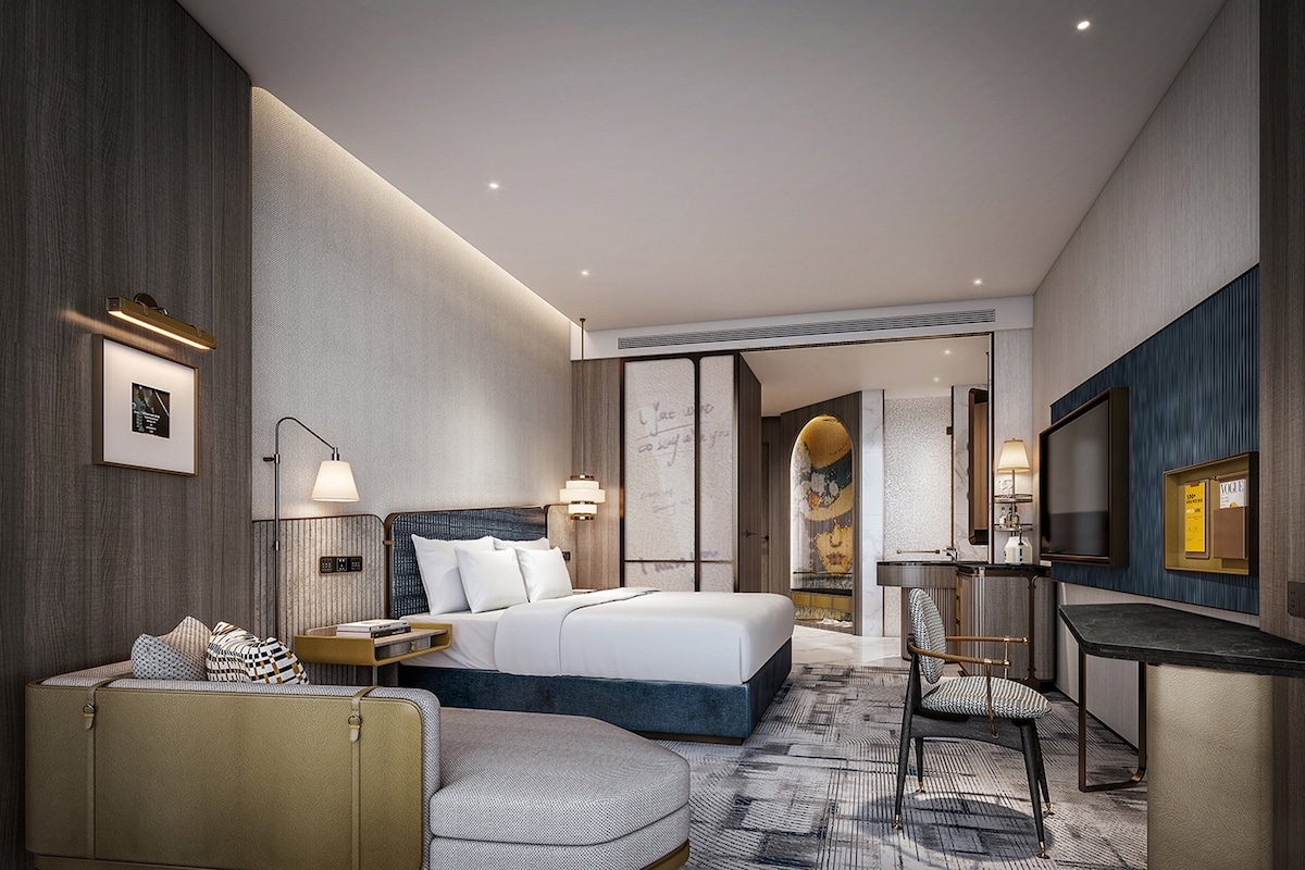 Une chambre d’hôtel moderne équipée d’un lit, d’une table de chevet, d’une lampe, d’un coin salon et d’un téléviseur.