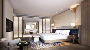 Une chambre d’hôtel moderne dotée d’un grand lit, d’un coin salon, d’une coiffeuse avec un miroir et d’une télévision.