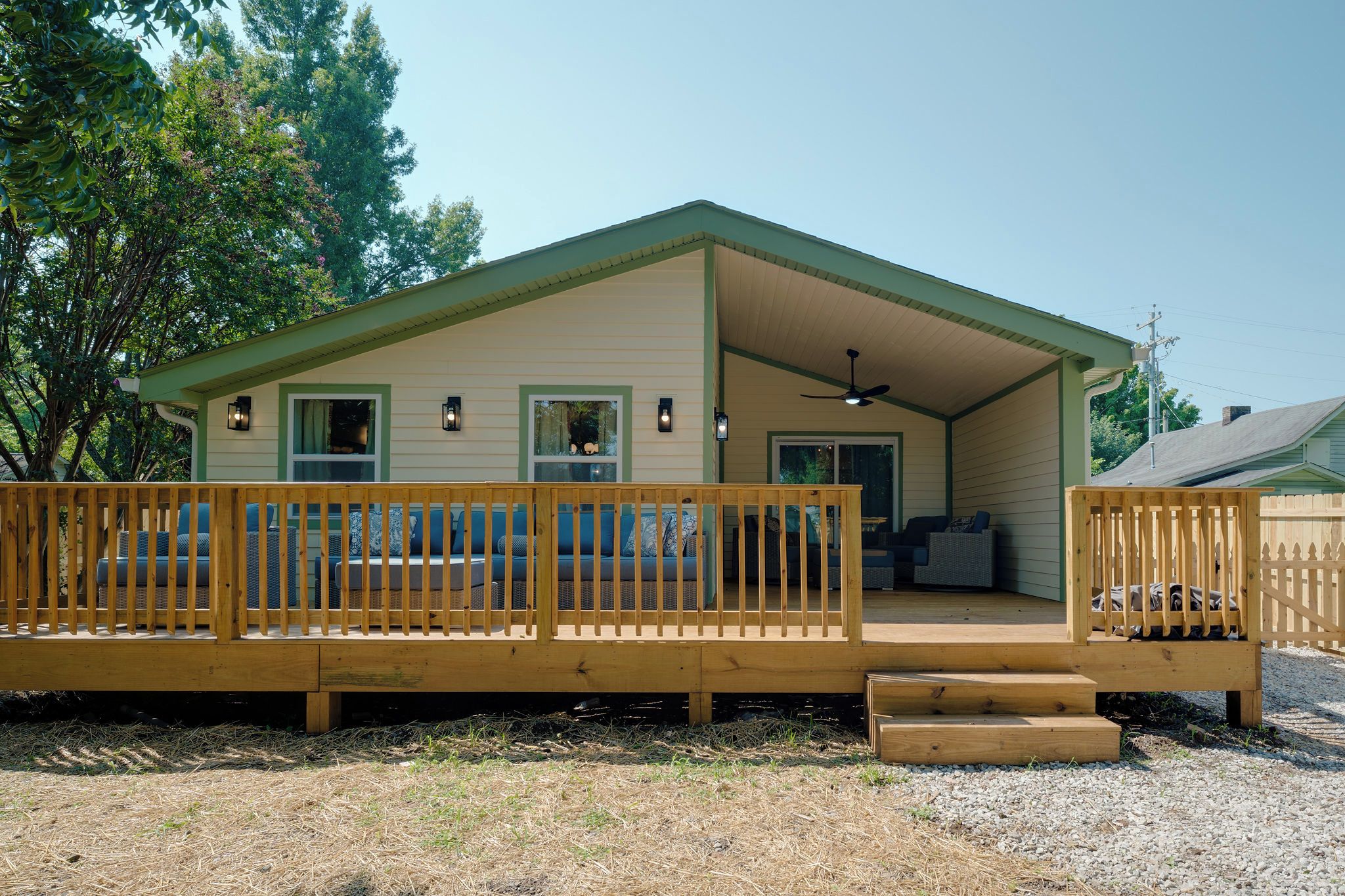 A two-story house with a covered porch, a fenced deck, and a small front yard.