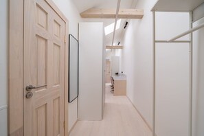 A narrow hallway with a wooden door, a mirror, and a small kitchenette area with a countertop and sink. - Stylish Scandi-Loft Gem with Exposed Brick & Beams (Riga)