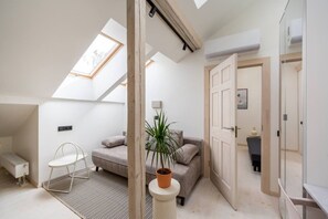 A modern loft bedroom with a skylight, a bed, a seating area, and a walk-in closet. - Stylish Scandi-Loft Gem with Exposed Brick & Beams (Riga)