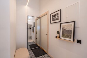 A hallway with a mirror, a door, and two framed pictures on the wall. - Stylish 2-Bedroom Attic Loft with AC & Workspaces (Rīga)