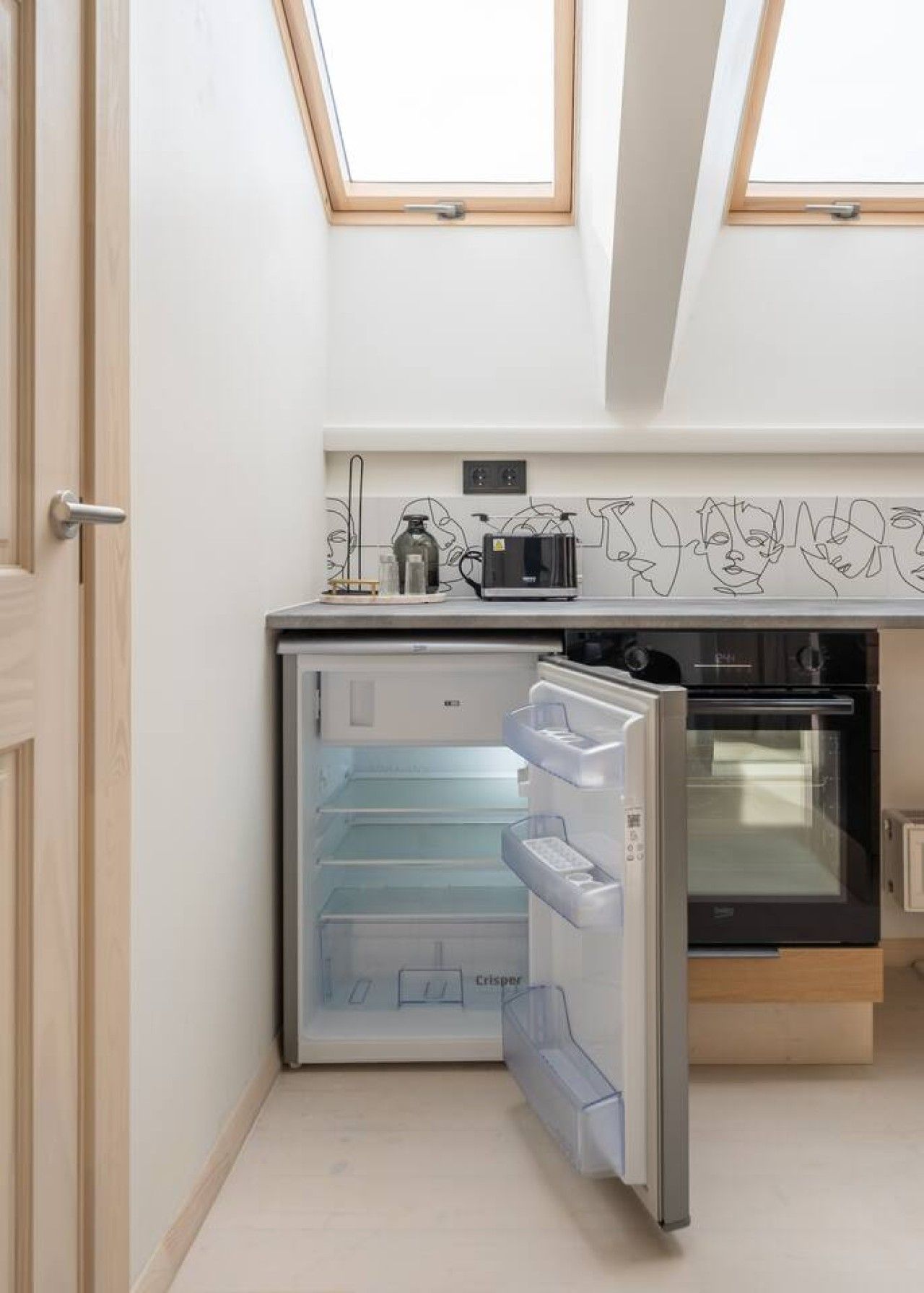A compact kitchen with a built-in refrigerator, oven, and a toaster.