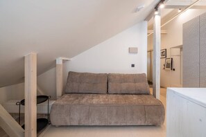 Ein Schlafzimmer im Loft-Stil mit einer eingebauten Schlafcouch, einem weißen Heizkörper und einer Treppe.