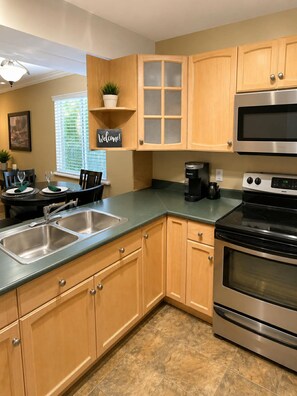 A modern kitchen with stainless steel appliances, wooden cabinetry, and a 'Welcome!' sign.