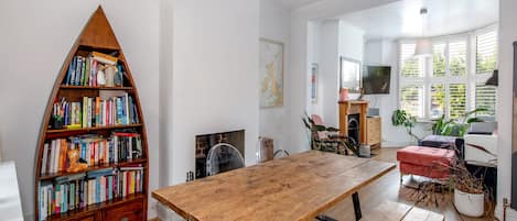 Ein geräumiger Raum mit Holztisch, Bücherregal, Kamin und Fernseher.