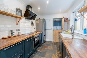 A modern kitchen with a built-in oven, a refrigerator, and a wooden countertop. - 2BR House with Courtyard Garden Near Taunton Rail (Taunton)