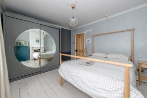 A bedroom with a bed, a circular mirror, a wardrobe, and a wooden headboard. - 2BR House with Courtyard Garden Near Taunton Rail (Taunton)