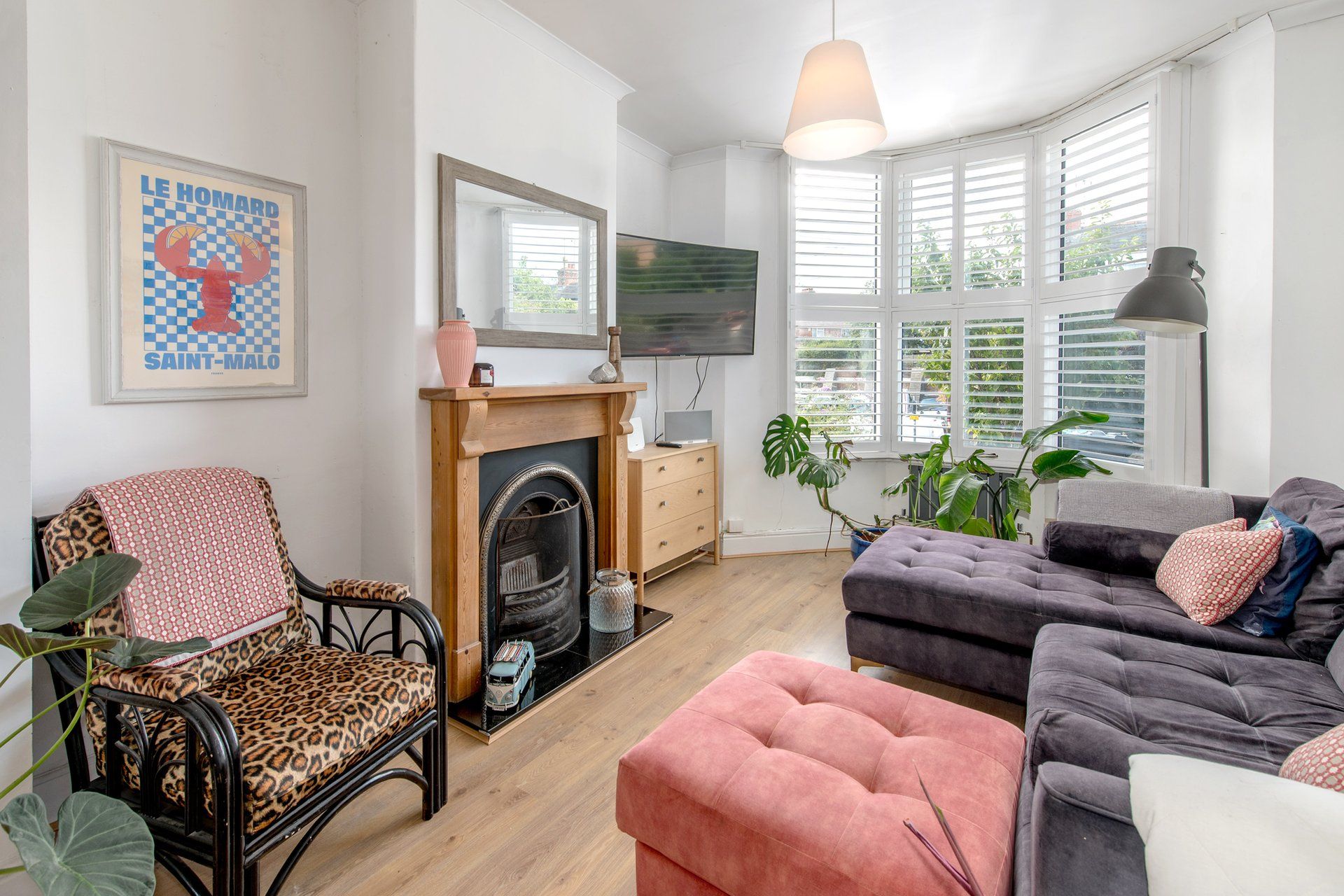 A living room with a fireplace, sofa, armchair, and a television.