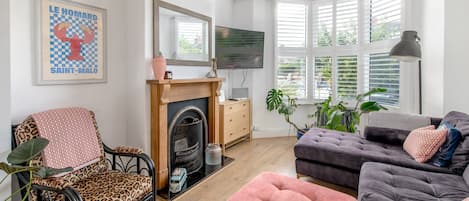 Ein Wohnzimmer mit Kamin, Sofa, Sessel und Fernseher.
