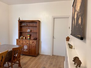 A room with a wooden cabinet, a dining table with chairs, a white door, and a wall-mounted picture. - Peaceful 2BR Home in Bearwood Near Lightwoods Park (Birmingham)