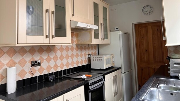 Una cocina equipada con microondas, estufa y refrigerador.