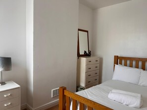 A bedroom with a bed, a dresser, a mirror, and a lamp. - Peaceful 2BR Home in Bearwood Near Lightwoods Park (Birmingham)
