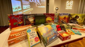 A hotel lobby with a table displaying various board games and a projection screen in the background.