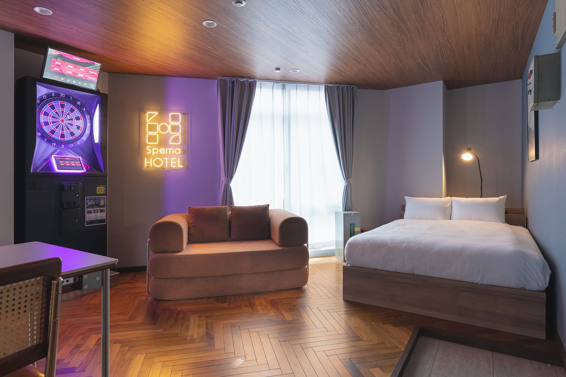 Ein Hotelzimmer mit einem Bett, einer Couch, einem Fernseher und einer Dartscheibe.