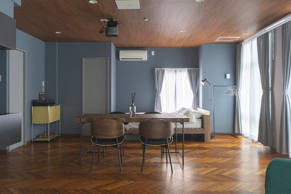 A modern room with a wooden ceiling, a bed, a desk with chairs, a standing lamp, and a large window with curtains. - SpemaHOTEL Kinshicho 5F (Sumida City)