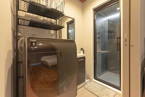 A compact room with a built-in washer-dryer unit, a small bed, and a sliding glass door leading to a shower area. - SpemaHOTEL Kinshicho 5F (Sumida City)