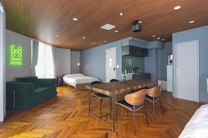 A hotel room with a wooden ceiling, a bed, a green sofa, a dining table with chairs, and a kitchenette. - SpemaHOTEL Kinshicho 5F (Sumida City)