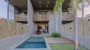 A modern outdoor pool area with a wooden deck, a small grassy area, and a bamboo fence. - House w 3 Suites n Pool 100m From the sea Hva0009 (Passo de Camaragibe)