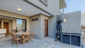 An outdoor patio with a round wooden table and chairs, a stone fireplace, and a view of the interior. - House w/ Pool 100m From the Beach Hva0002 (Passo de Camaragibe)