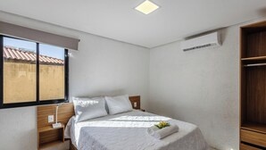 A bedroom with a bed, a bedside table, a window, and a built-in wardrobe. - House w/ Pool 100m From the Beach Hva0002 (Passo de Camaragibe)