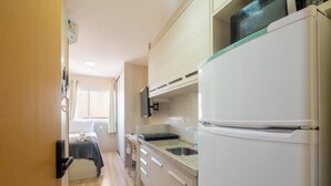 Cozinha compacta com geladeira, micro-ondas e pia.