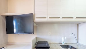 Cozinha com televisão de tela plana na parede, pia e bancada.