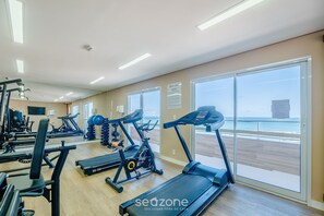 Une salle de sport équipée de tapis de course, de vélos d’exercice et d’appareils de musculation.