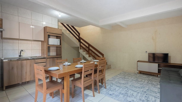 A compact living space with a kitchen, dining area, and a staircase leading to an upper level.