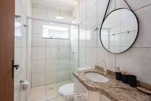 A bathroom with a glass-enclosed shower, a sink with a marble countertop, and a round mirror. - House w/ BBQ Area 110 m From the Beach Oni0003 (Barra Velha)