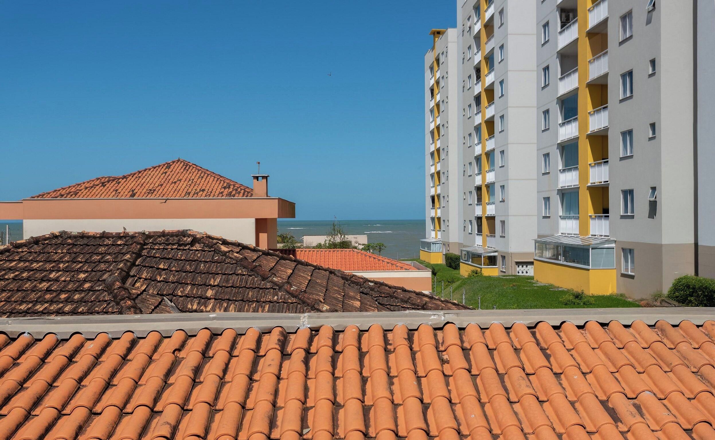 A residential building with a tiled roof, a balcony, and a view of the sea.