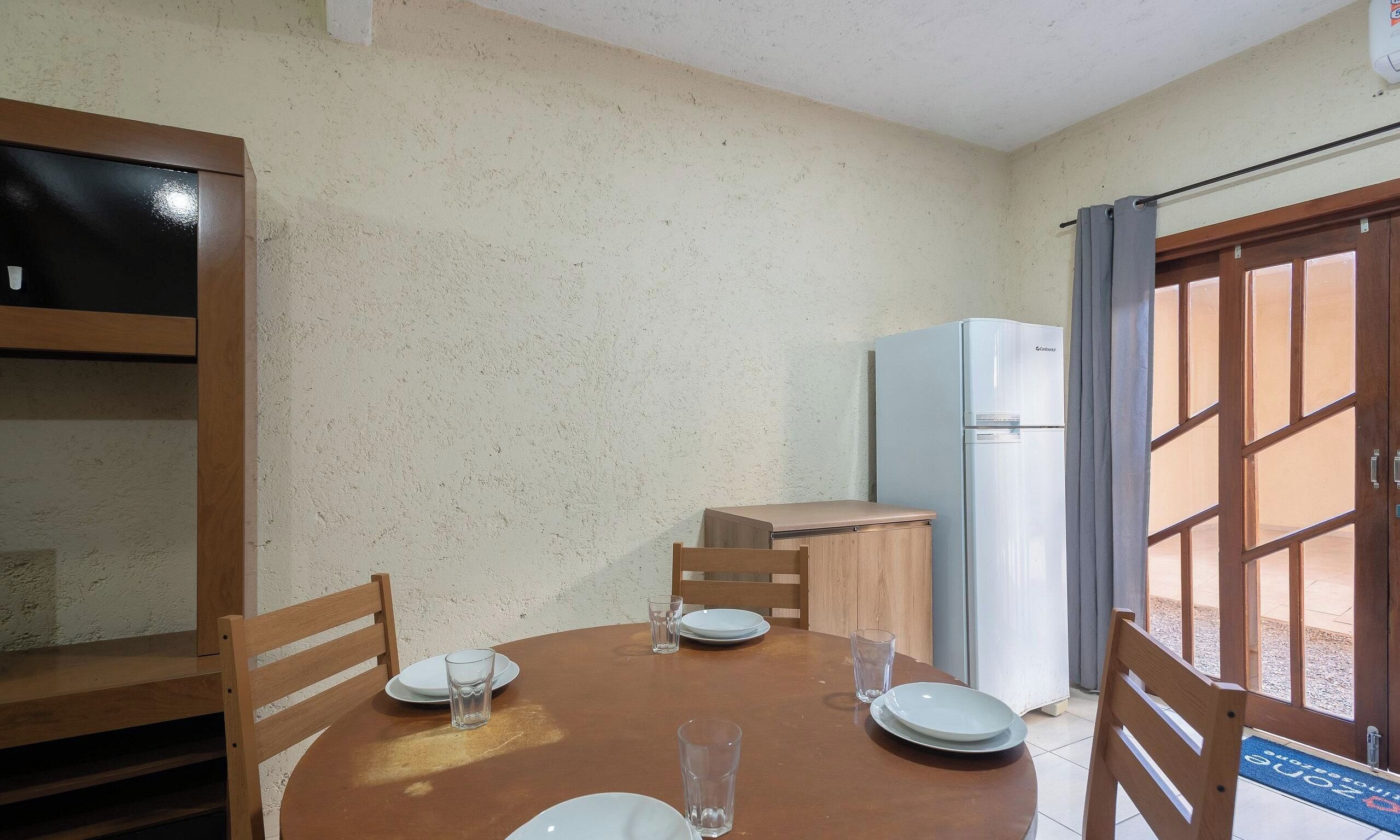 A dining area with a round table, chairs, and a refrigerator.