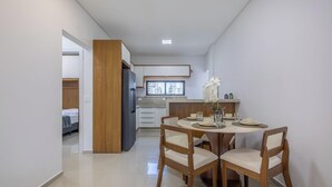 Ett modernt kök med ett inbyggt kylskåp, en matplats med ett runt bord och stolar, och utsikt över staden genom ett fönster.