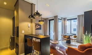 A modern hotel room with a dining area, a large window, and a view of the outdoors. - Modern Apartment Facing Praca das Etnias Cbg0306 (Gramado)
