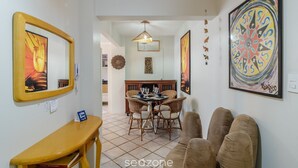 Zona pranzo con tavolo rotondo, sedie in vimini e lampadario.