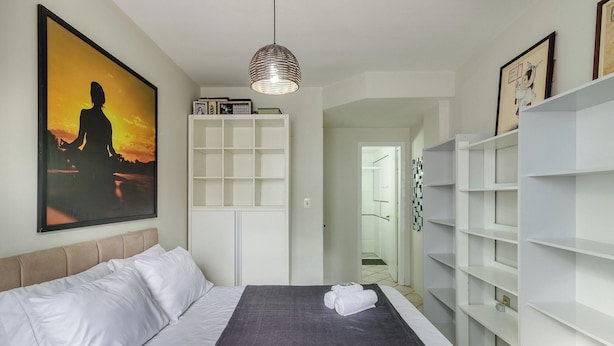 Una camera d'albergo con un letto, un quadro grande, un armadio e un corridoio che porta al bagno.