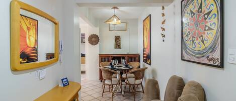 Un coin repas avec une table ronde, des chaises en osier et un luminaire suspendu.