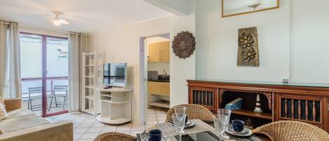 A modern living room with a dining area, a TV, and a balcony with a view.