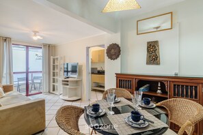 Uma sala de estar moderna com área de jantar, televisão e varanda com vista.