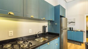 A modern kitchen with blue cabinets, stainless steel appliances, and a black countertop. - Elegant apt in the Heart of Gramado Cbg0106 (Gramado)