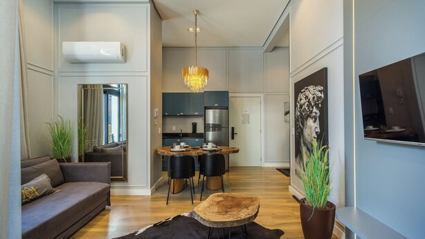 A modern living room with a sofa, a dining table with chairs, a chandelier, and a large painting on the wall. - Elegant apt in the Heart of Gramado Cbg0106 (Gramado)