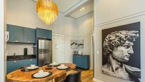 A modern kitchen with teal cabinets, a stainless steel refrigerator, and a dining area with a wooden table and chairs. - Elegant apt in the Heart of Gramado Cbg0106 (Gramado)